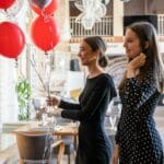 Dwie eleganckie kobiety świętują urodziny z czerwonymi balonami indoors