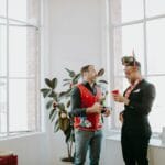 Dwoje współpracowników w świątecznych swetrach na biurowym przyjęciu