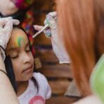 Dziewczynka z malowaną twarzą na kolorowym przyjęciu dziecięcym