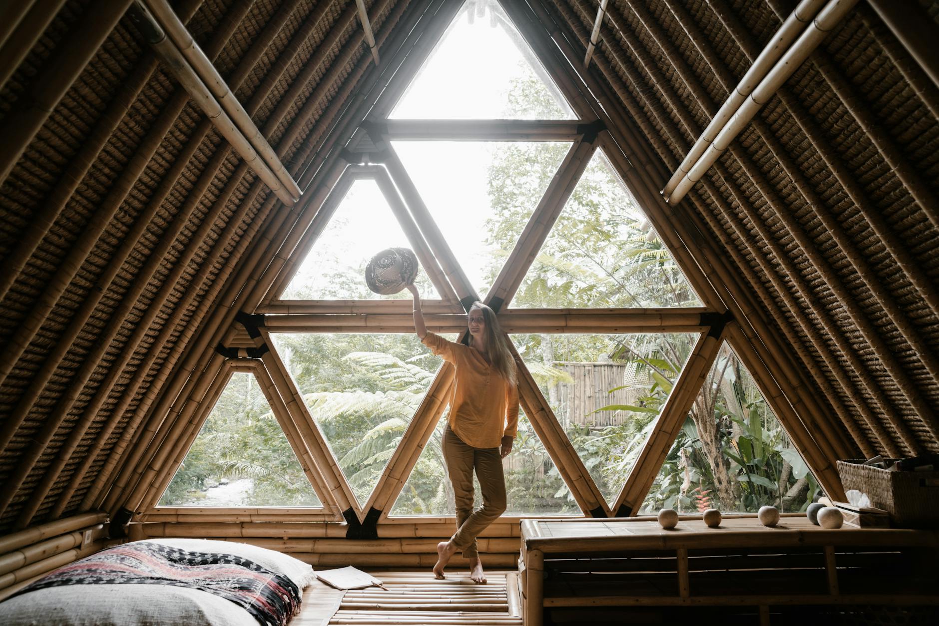 Kobieta w bambusowym domu z trójkątnymi oknami wśród tropikalnych roślin