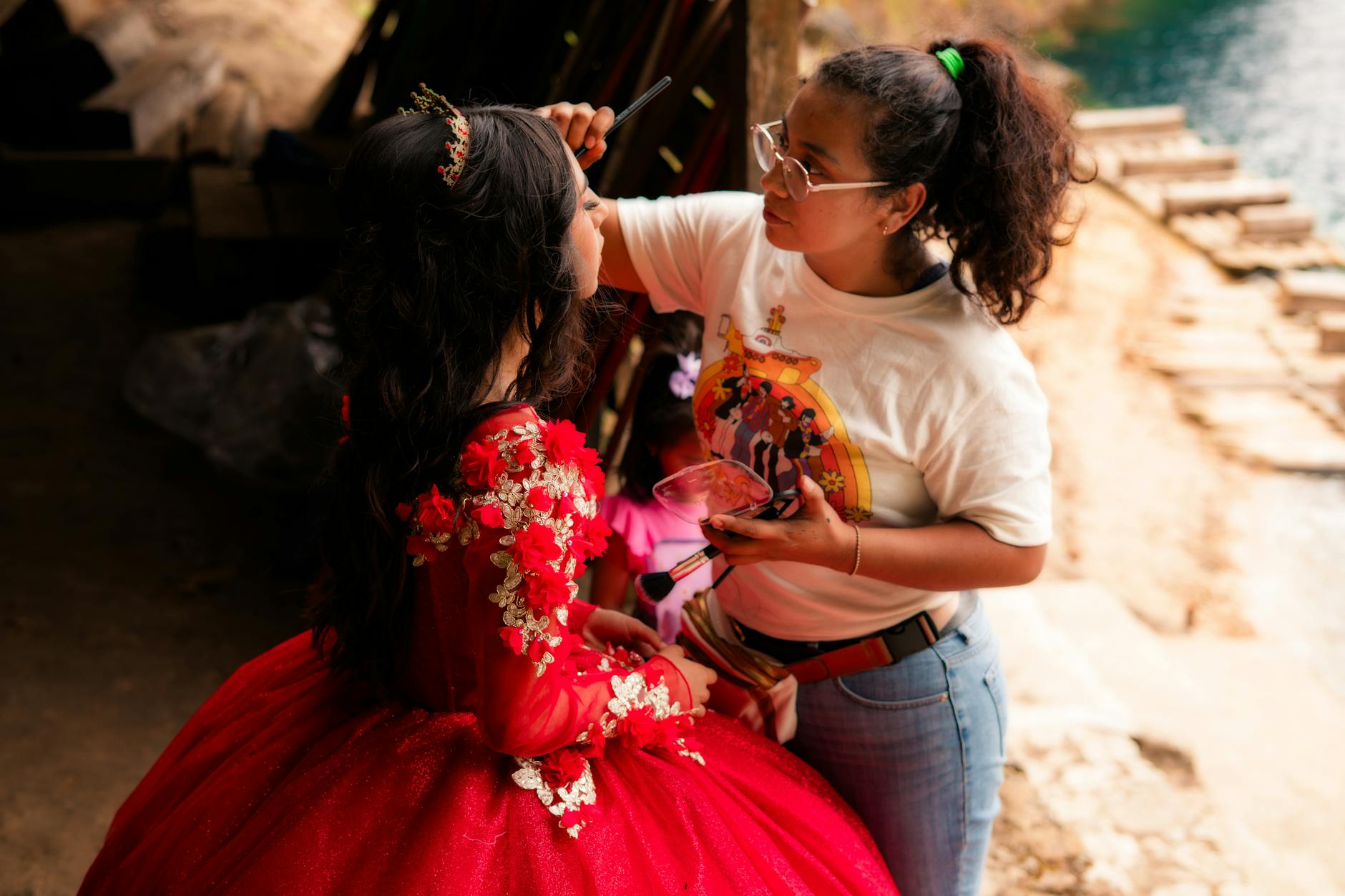 Makijażystka robi makijaż młodej kobiecie w czerwonej sukience na dworze