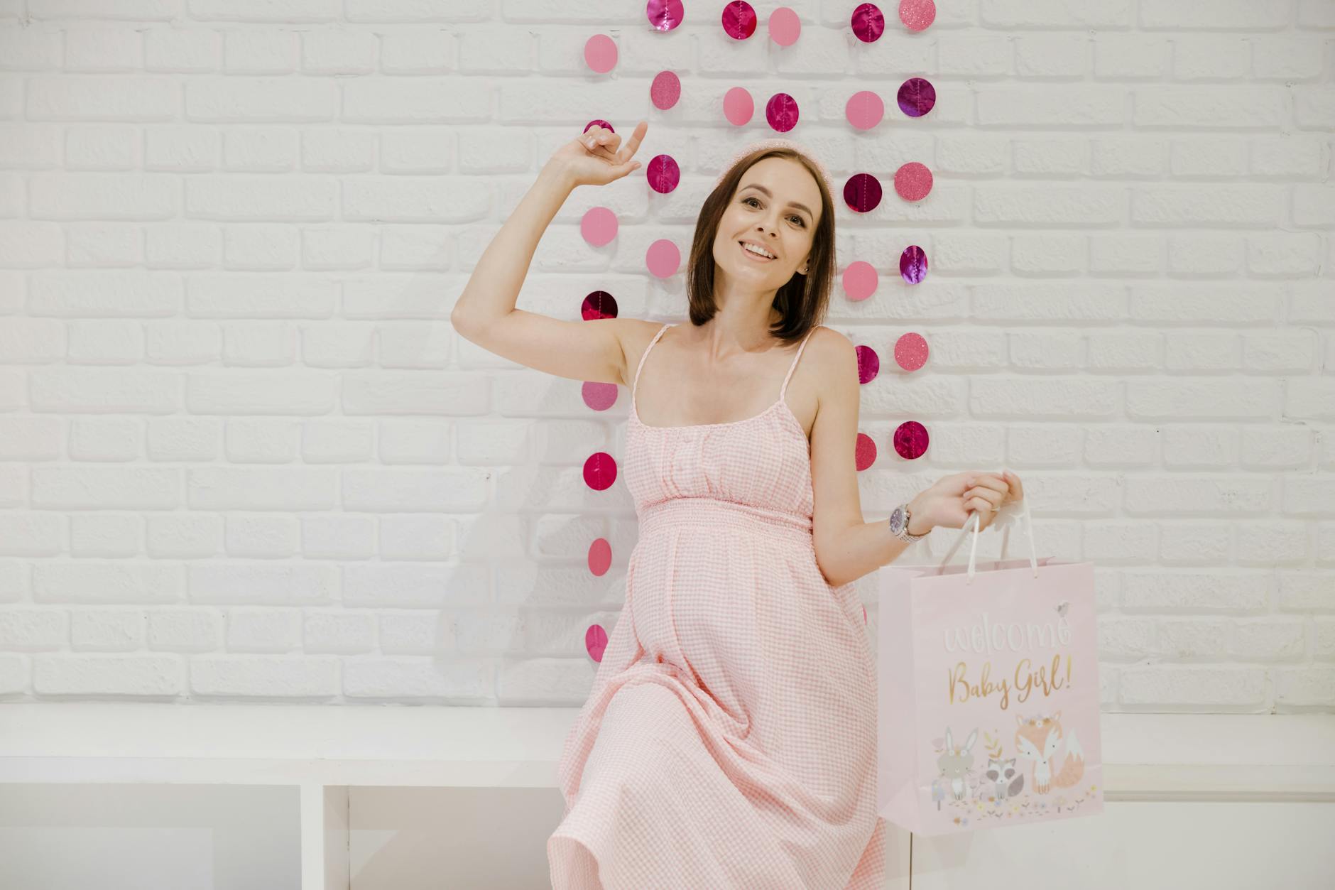 Uśmiechnięta ciężarna w różowej sukience na baby shower w restauracji