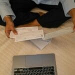 Dłonie trzymające czeki przy laptopie podczas planowania płatności