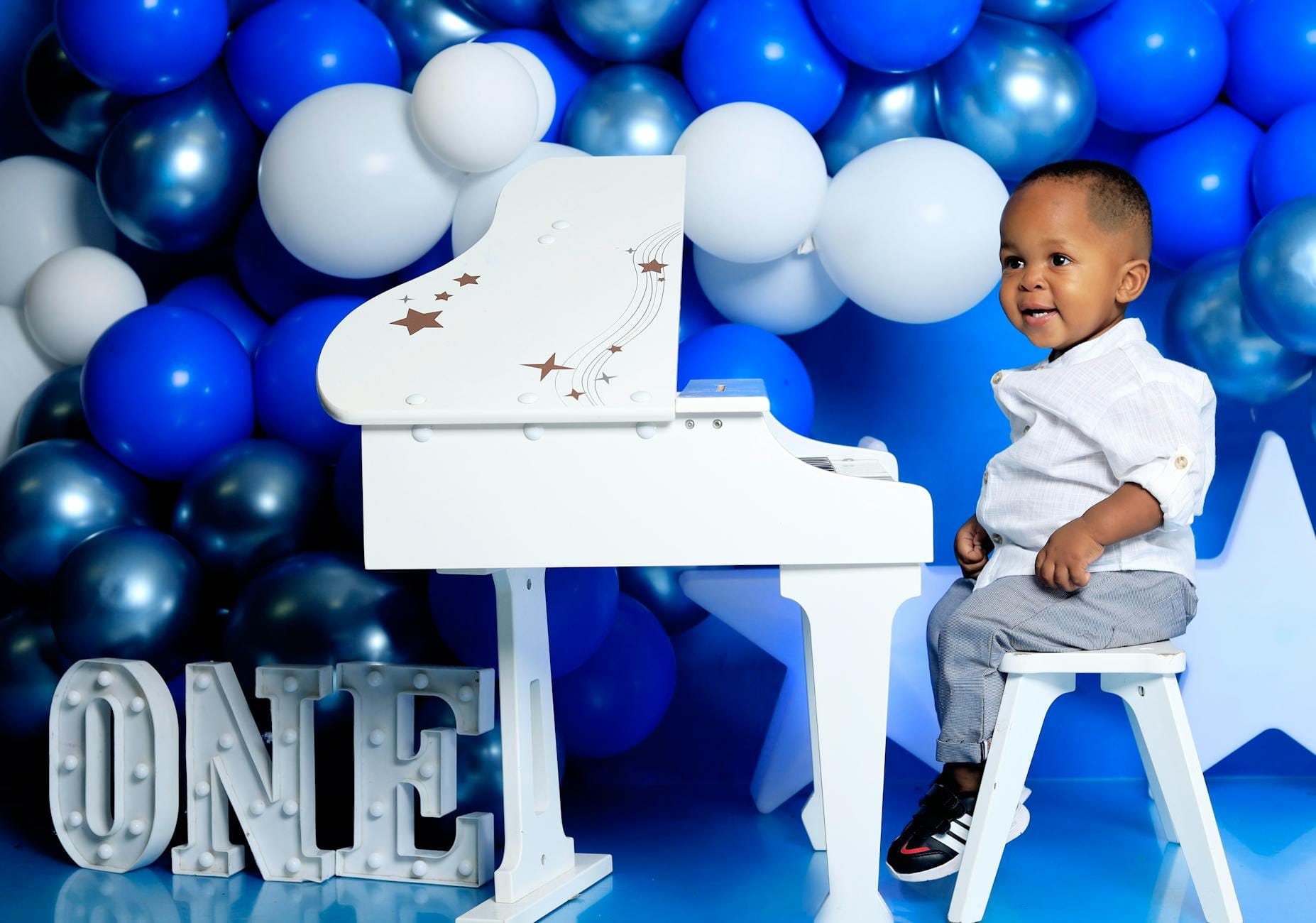 Animacje i zabawy z muzyką na komunii: scenariusz na 2 godziny Małe dziecko przy białym pianinie na tle niebieskich balonów