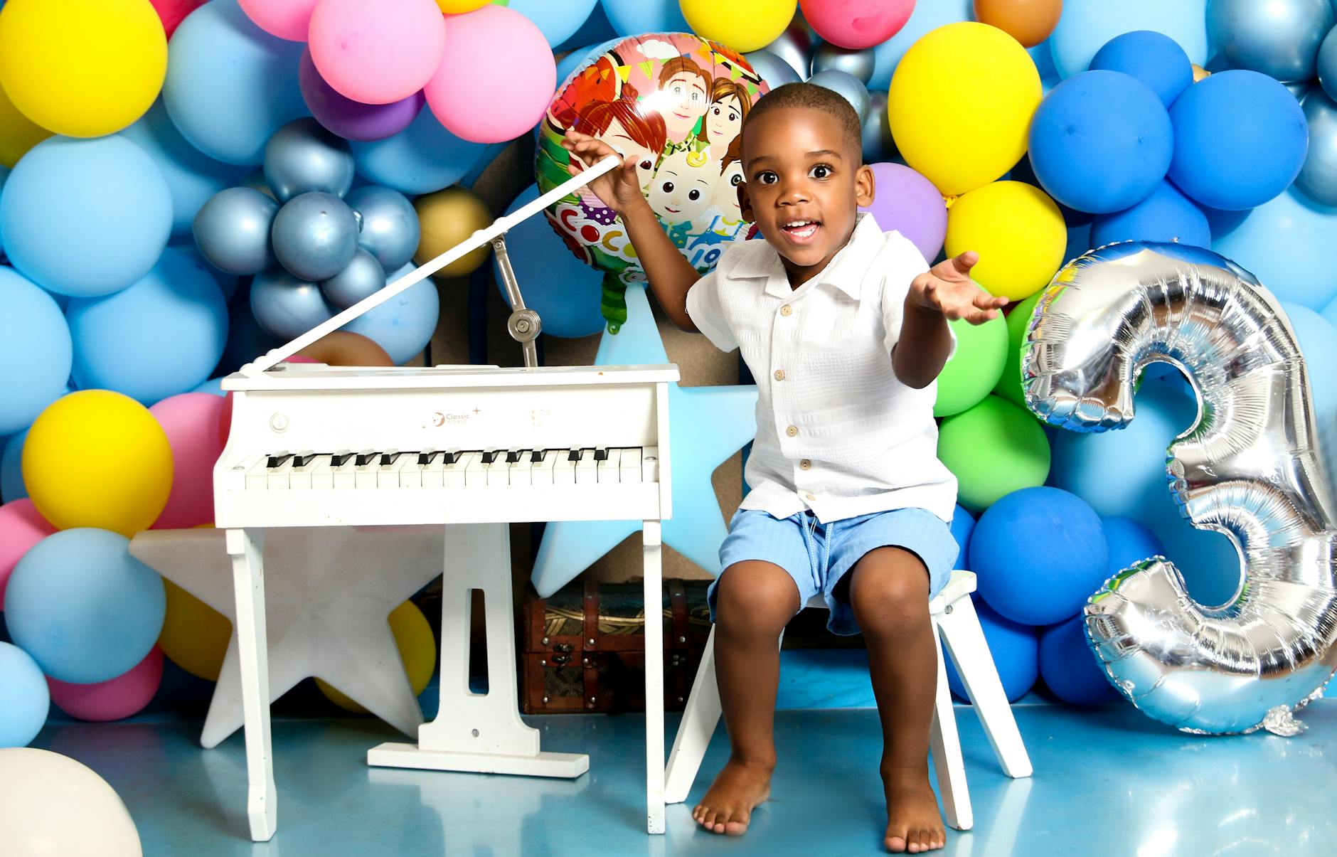 Uśmiechnięte dziecko bawi się przy kolorowych balonach i małym pianinku